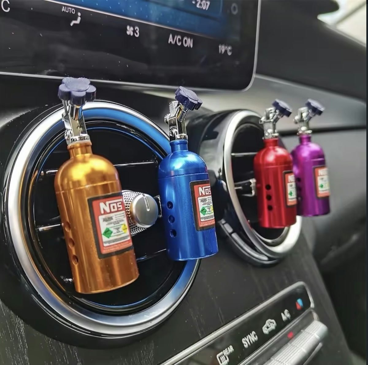 Four nitrous bottle vent clip perfumes clipped to a car's round air vents